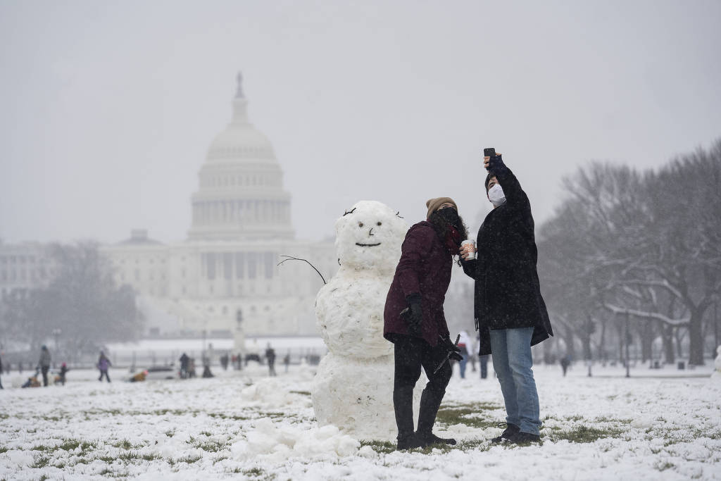 Pessoas tiram fotos com boneco de neve e o prédio do Capitólio ao fundo, em Washington.